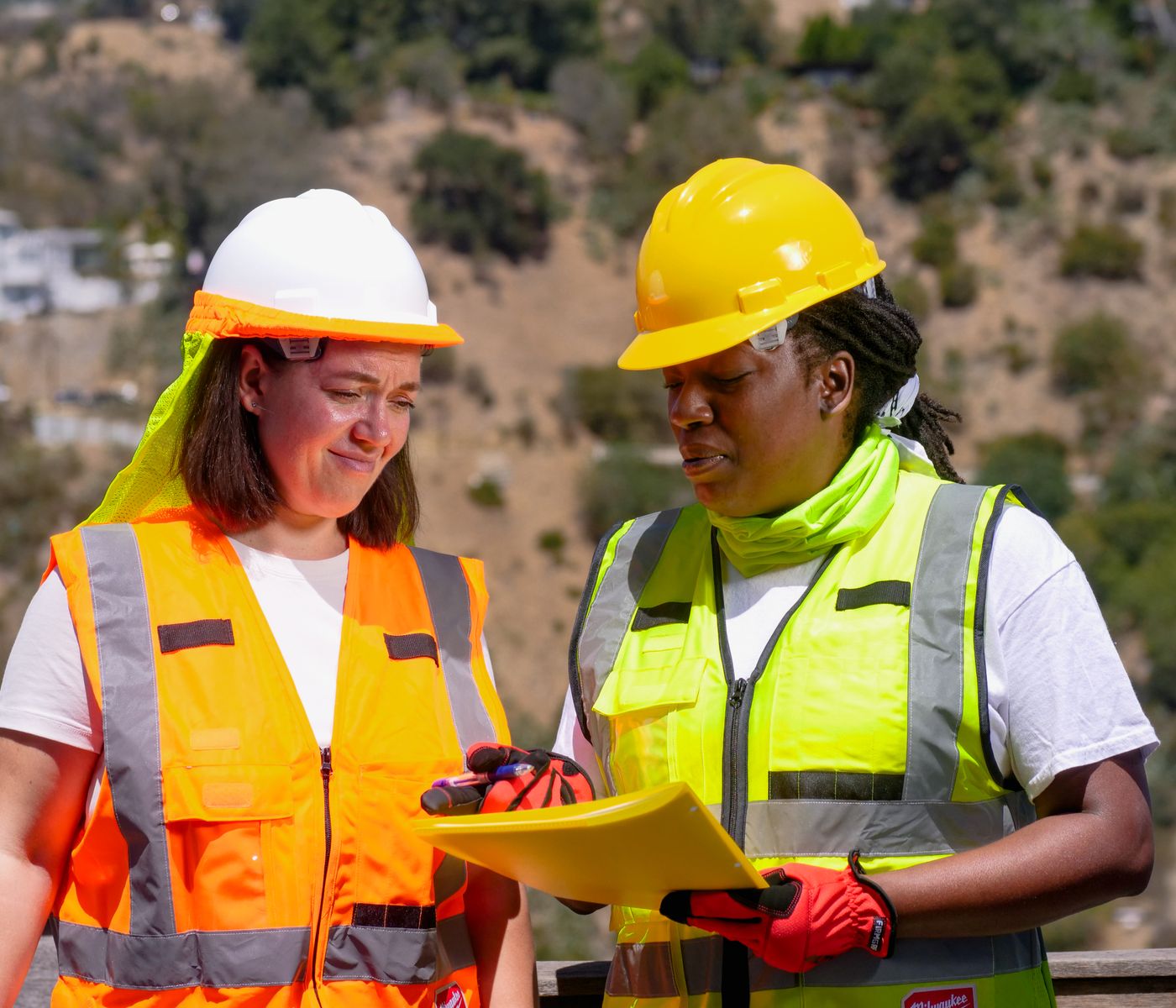 Construction compliance professional reviewing a project clipboard inside an active worksite